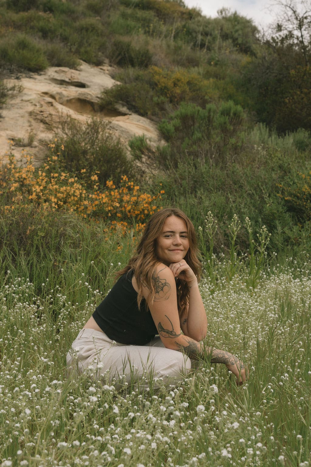 Devon Shae sitting in a field near the coast for a brand photoshoot